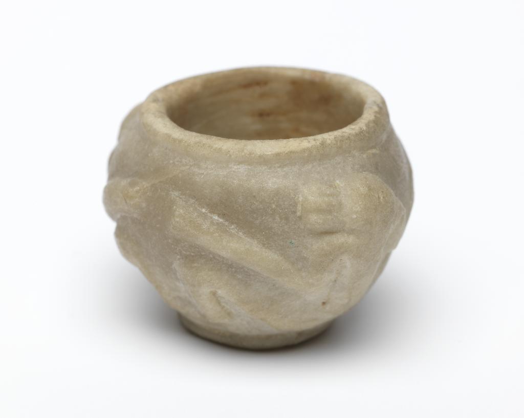 An image of Stone vessel. Calcite vessel with monkeys. Jar, squat, with two monkeys on outside in relief. Used as an eye-paint jar. Production Place/Find Spot:: Egypt. Calcite, carved, height 2.2 cm, 1976-1794 B.C. Dynasty 12.