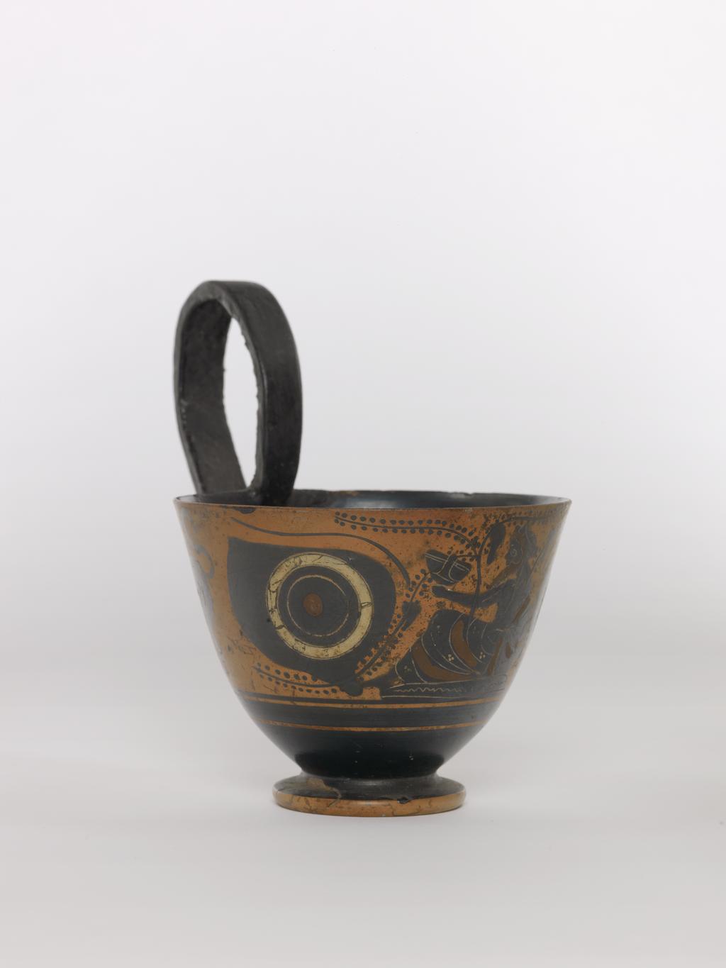 An image of Vessel. Kyathos, Dionysos and lions. Production Place: Athens, Attica, Greece. Clay, black-figured, height 0.076 m, diameter, rim, 0.099 m, diameter, base, 0.049 m, height 0.131 m, 500 B.C. Archaic Period.