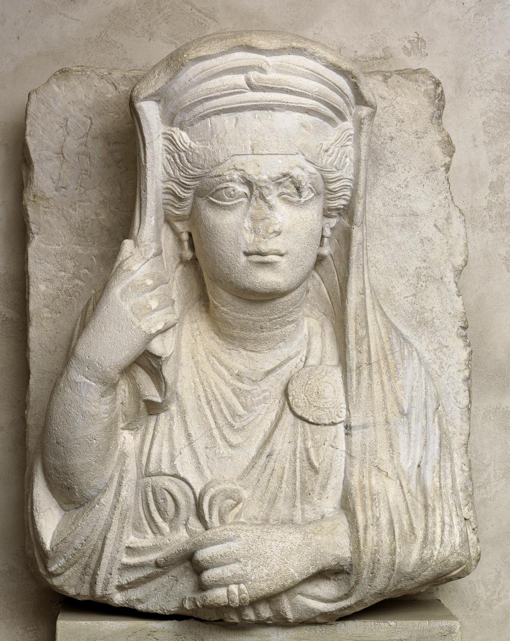 An image of Funerary equipment, grave relief. Woman, from a Funerary Monument. Find Spot: Palmyra Syria. Limestone, carved & inscribed, height 0.485 m, width (relief) 0.116m. Middle Roman, 101- 200 AD.