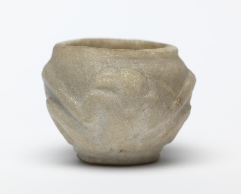 An image of Stone vessel. Calcite vessel with monkeys. Jar, squat, with two monkeys on outside in relief. Used as an eye-paint jar. Production Place/Find Spot:: Egypt. Calcite, carved, height 2.2 cm, 1976-1794 B.C. Dynasty 12.
