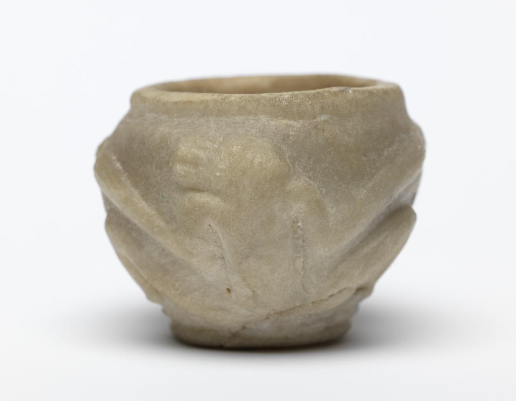 An image of Stone vessel. Calcite vessel with monkeys. Jar, squat, with two monkeys on outside in relief. Used as an eye-paint jar. Production Place/Find Spot:: Egypt. Calcite, carved, height 2.2 cm, 1976-1794 B.C. Dynasty 12.
