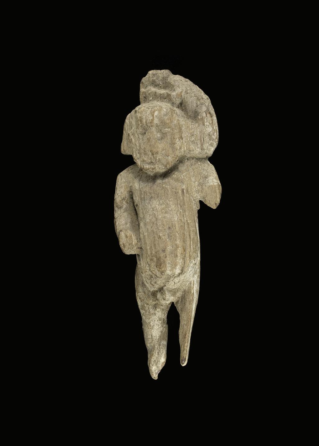 An image of Figure/statuette. Pygmy (?), striding, carrying monkey on shoulder. Find Spot: Amarna, el- (?), Egypt.  Production Place: Egypt. Wood, height 0.084 m, length 0.027 m, width 0.03 m.