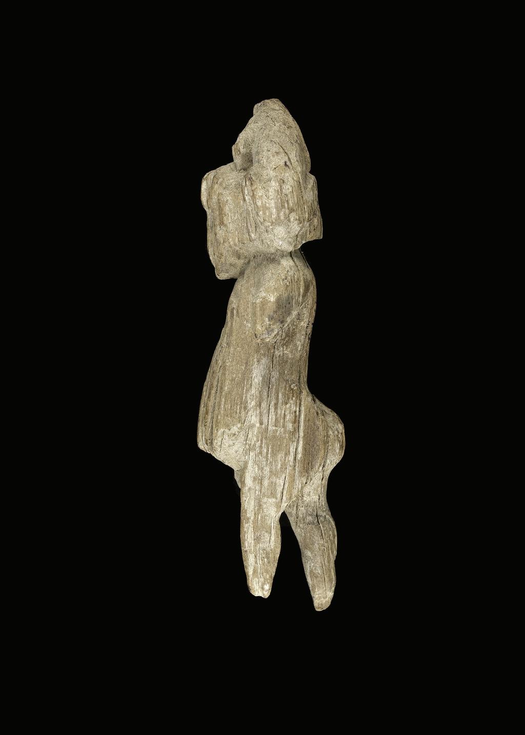 An image of Figure/statuette. Pygmy (?), striding, carrying monkey on shoulder. Find Spot: Amarna, el- (?), Egypt.  Production Place: Egypt. Wood, height 0.084 m, length 0.027 m, width 0.03 m.