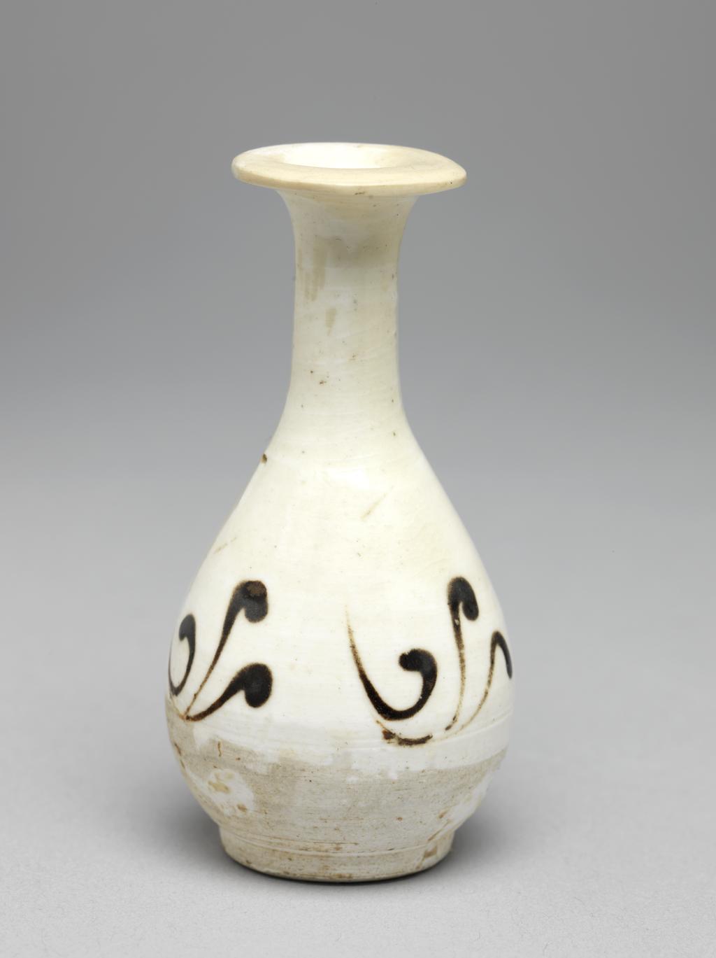 An image of Miniature vase. Cizhou ware. Piriform with a long slender neck and wide flat rim, standing on a footring. The sides are decorated with three groups of three curved brown strokes. The lower part of the vase and base are undecorated. White stoneware, decorated in dark brown on a white slip ground, under a transparent colourless glaze, height 7.2 cm, 1000-1127. Northern Song (960-1127). Chinese. Acquisition Credit: Lent to the museum by Helen H. L. Whittow (nee Malcolm).