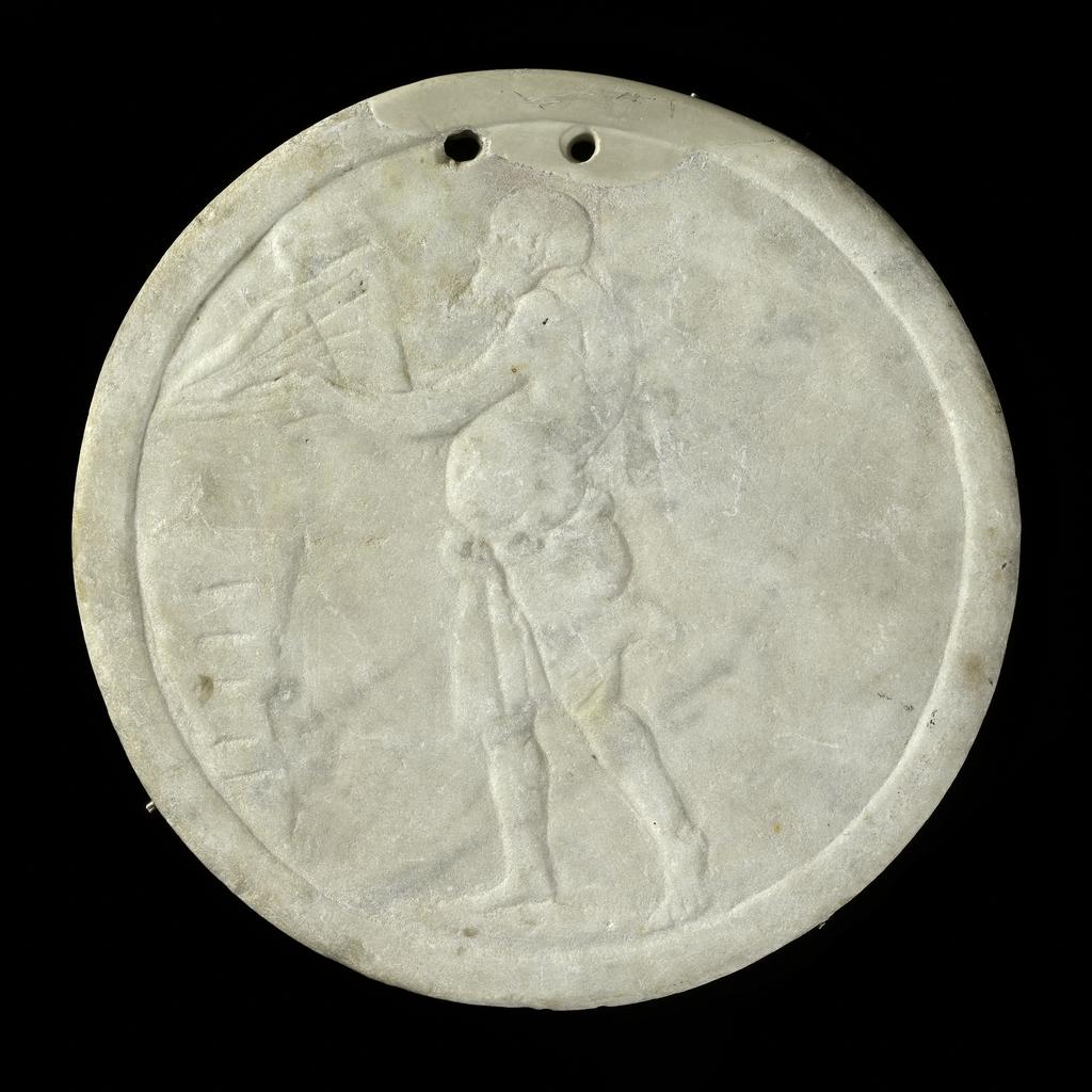 An image of Oscillum, with relief of a satyr on one side. Carved Luna marble, height 0.258 m, 1-200 AD. Early Roman Period. Production Place: Italy.