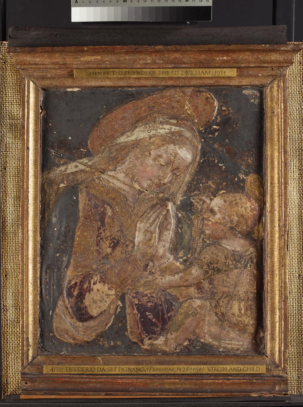 An image of Sculpture. Virgin and Child. Desiderio da Settignano, after (Italian, 1428-1464). Relief of the Virgin and Child, painted and gilt stucco. The half-length Virgin is shown in three-quarter view, in the act of praying over Christ Child. The Virgin has long, curly hair which flows behind her right shoulder. She is finely painted, and special care has been given to the decoration of her scarlet robe, veil and halo. The Christ Child, seen in profile, is sitting in front of his mother. He is dressed in a robe and a tall waist-belt and he is indicating the Virgin with his left hand, whilst clasping an end of the Virgin’s veil with his right hand. The halo of Christ Child is also finely decorated. The figures are set against a flat painted background. Stucco, painted and gilded, height, frame, 57.1 cm, width 43.4 cm, depth 7 cm, height, object, 52 cm, width 43.2 cm, depth 6.5 cm, circa 1450-circa 1460. Renaissance. Florentine School.