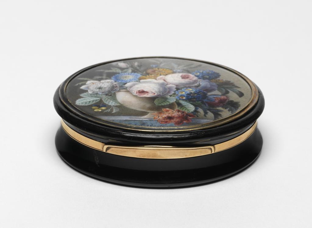 An image of Miniature. Tortoise-shell box with a miniature of flowers in a stone vase on a marble slab. Redouté, Pierre Joseph (Flemish, 1759-1840). Unknown box maker. Tortoise-shell and gold with a miniature in watercolour and bodycolour on card, mounted in gilt metal and set under glass. The circular miniature depicts a pale stone vase of flowers, including heartsease, anemones, blue aster, marigolds, campanula, auricula and centifolia roses, on a marble slab. Height (whole box) 2.8 cm, diameter (whole box) 8.5 cm, 1827-1840. Acquisition: bequeathed 1973 by Henry Rogers Broughton Fairhaven.