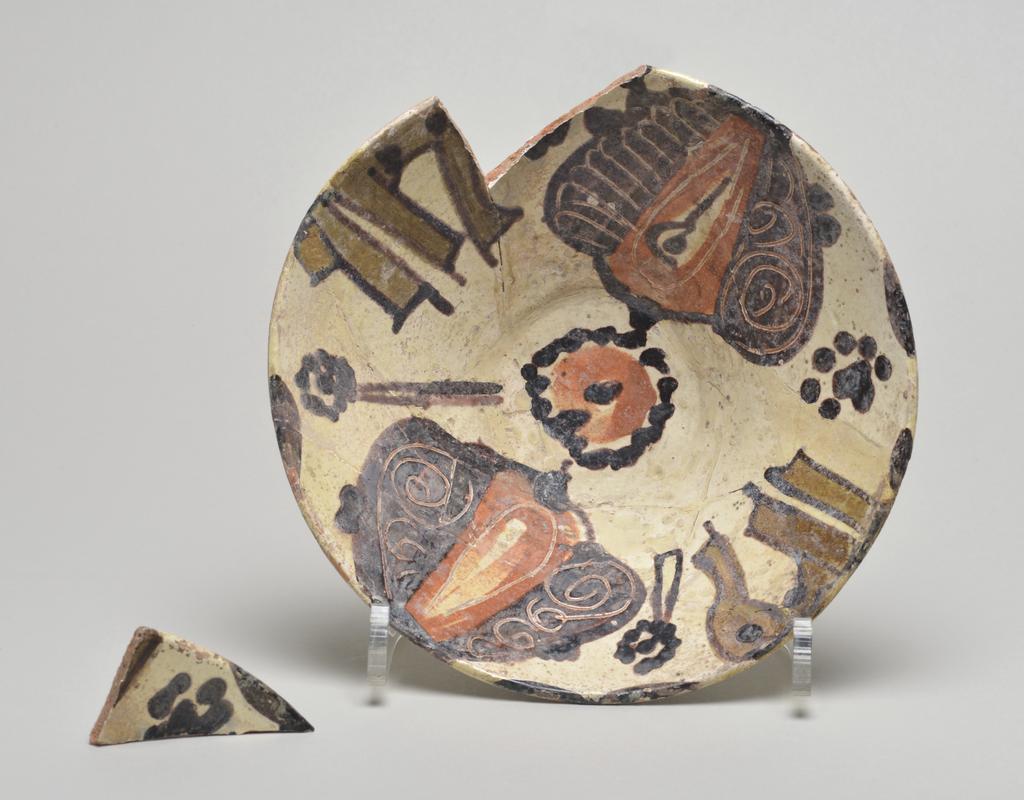 An image of Studio Ceramics. Earthenware bowl with a white slip over the buff body. Black, red and olive slip decoration, of two palmettes and other forms. Production Place: Nishapur, Iran (probably). 900-999. Acquisition: Dr John Shakeshaft Bequest.