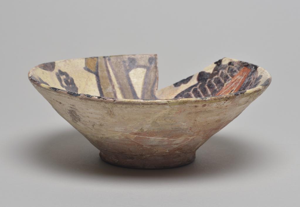 An image of Studio Ceramics. Earthenware bowl with a white slip over the buff body. Black, red and olive slip decoration, of two palmettes and other forms. Production Place: Nishapur, Iran (probably). 900-999. Acquisition: Dr John Shakeshaft Bequest.