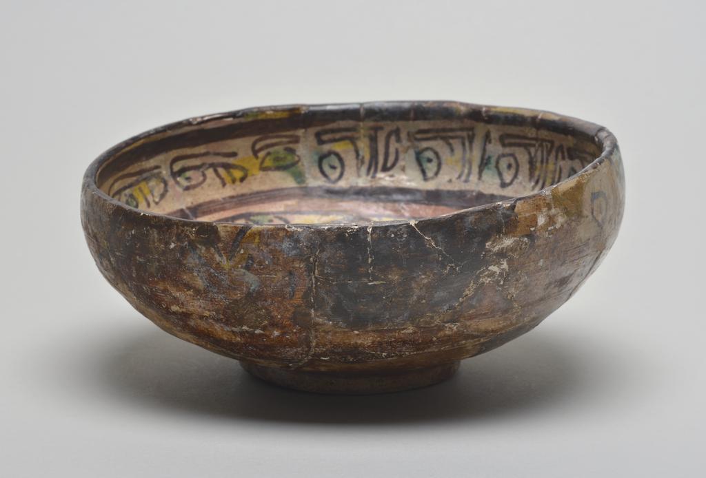 An image of Studio Ceramics.' Buffware' earthenware footed bowl. Underglaze painted in black and red slip, also yellow and green. Featuring gazelle, bird, flowers, and other motifs. Production Place: Nishapur, Iran. 900-999. Acquisition: Dr John Shakeshaft Bequest.