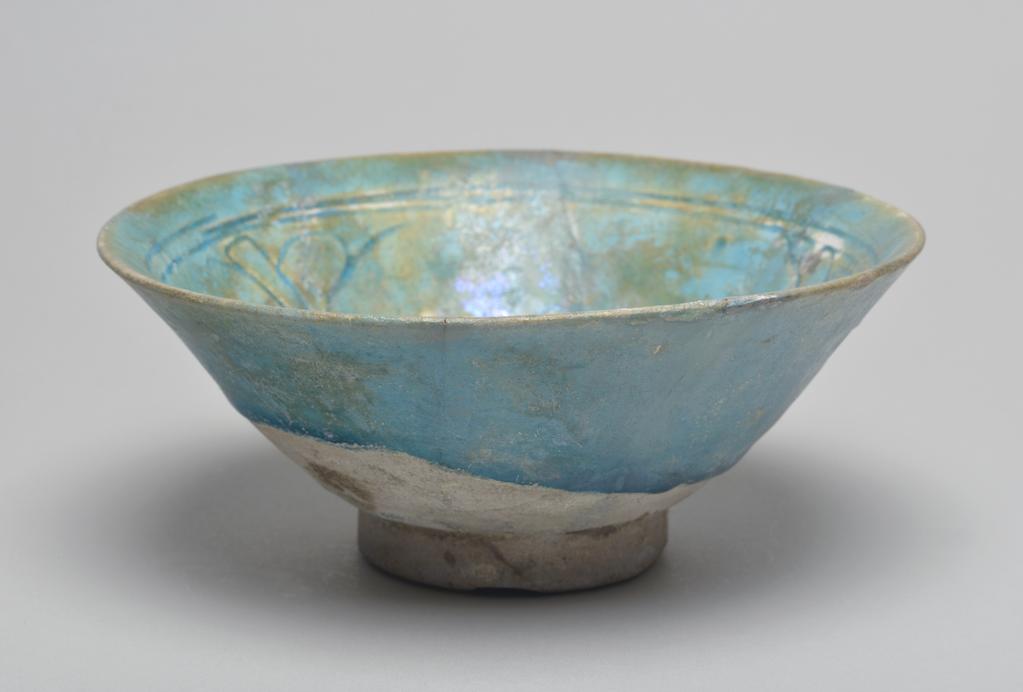 An image of Studio Ceramics. Fritware bowl. Covered in a turquoise (copper) glaze with iridescence. Incised floral decoration in well. Islamic. Acquisition: Dr John Shakeshaft Bequest.