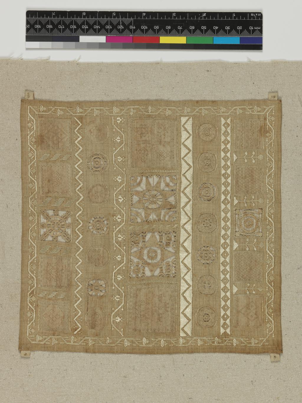 An image of Textiles. Whitework sampler. Slade, Ursula (English). The sampler is almost square in shape and is made up of inserted panels of hollie point and needle lace, neatly divided and bordered by repeat patterns in counted satin stitch. The sampler carries the inscription 'VrsVla/Slade' in the middle right panel. Linen embroidered with linen thread in satin and back stitch with hollie point and needle lace insertions. All the edges are hemmed. Length 21.75 cm, width 21 cm, 1728.