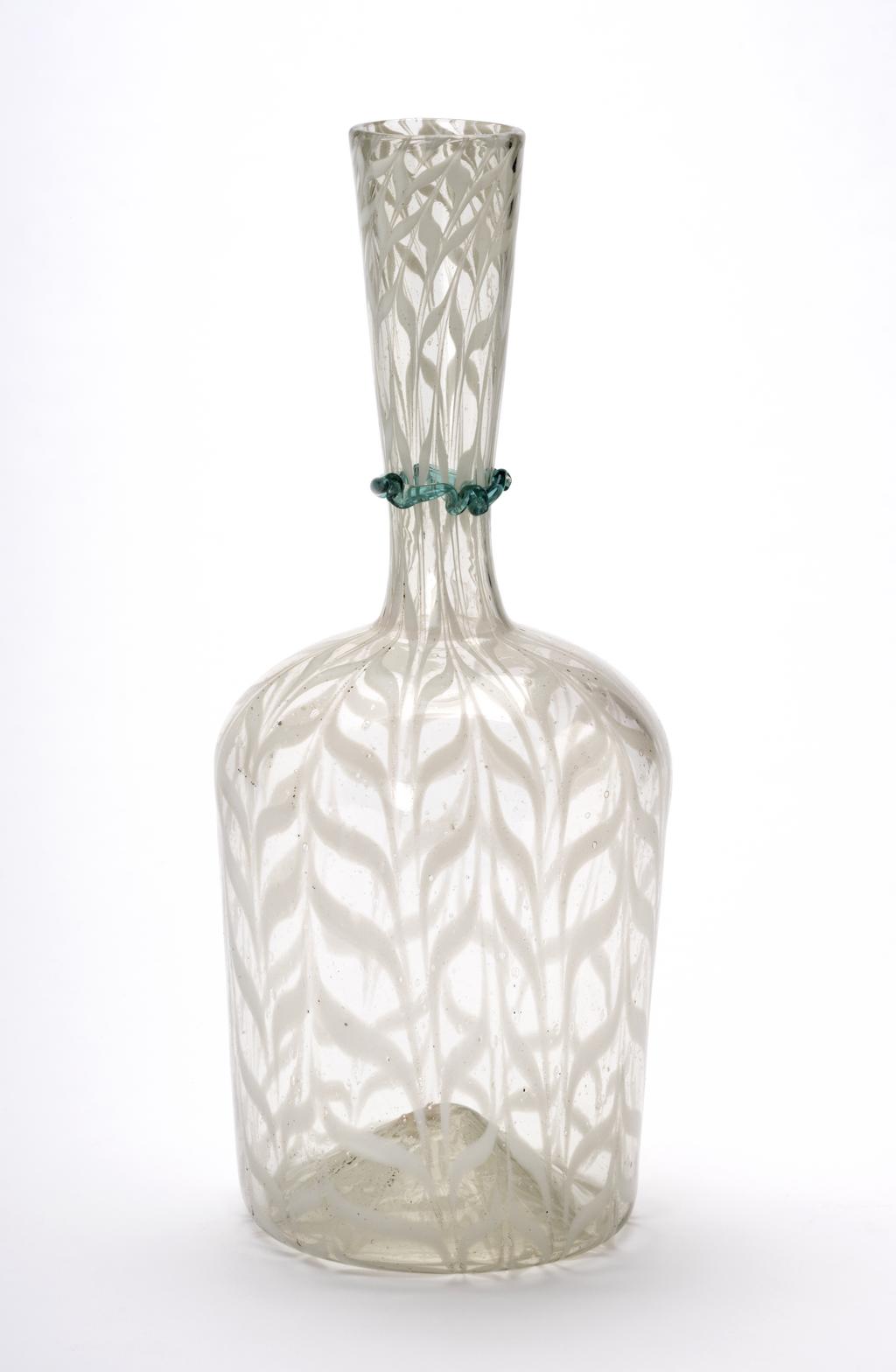 An image of Continental glass. Carafe. Façon de Venise. Unknown glasshouse, Spain, Catalonia, Barcelona. Clear greenish glass carafe or bottle, with white combed trailing, and dark turquoise undulating cord round the neck. Clear glass with combing, height, 21.7 cm, width, 8.8 cm, after 1550 to before 1650. Sir Ivor and Lady Batchelor Bequest.