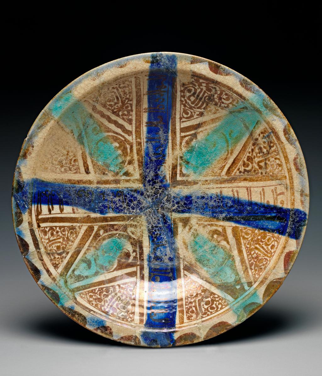 An image of Fritware (stonepaste) / Dish. Unknown Maker. Pinkish-buff fritware, wheel thrown, with a pitted, blue and cream crazed glaze painted with turquoise and blue pigment and lustre, height 7.5 cm, width 36.7 cm, diameter (rim) 36.7 cm, diameter (base) 16 cm, circa 1179-1198. Seljuk; Monumental style. Iranian.