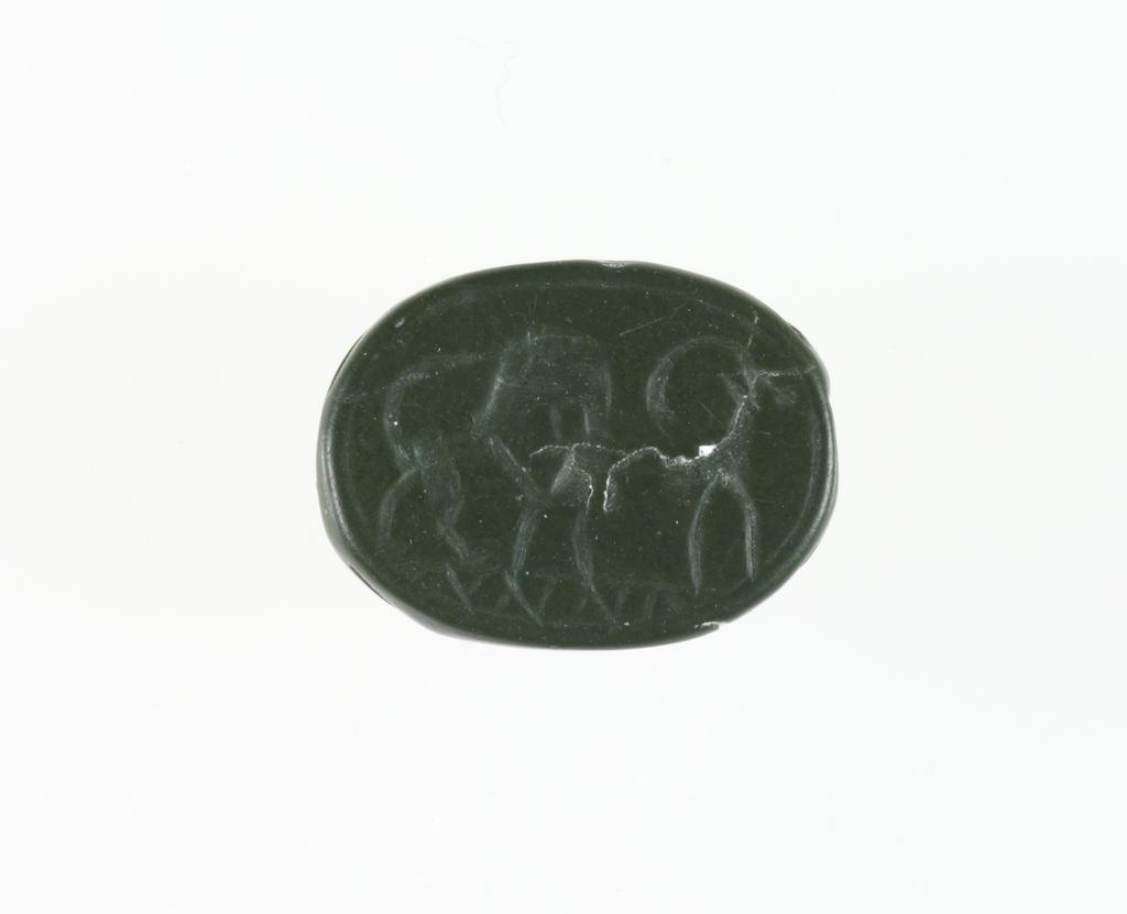 An image of Engraved gems/Scarab/Intaglio Cutting. Lion, leaping onto back of goat/ibex, in profile to left. Green steatite, height 15 mm, width 11.5 mm, depth 7.5 mm, circa 600-501 B.C. Phoenician, Greek influence.