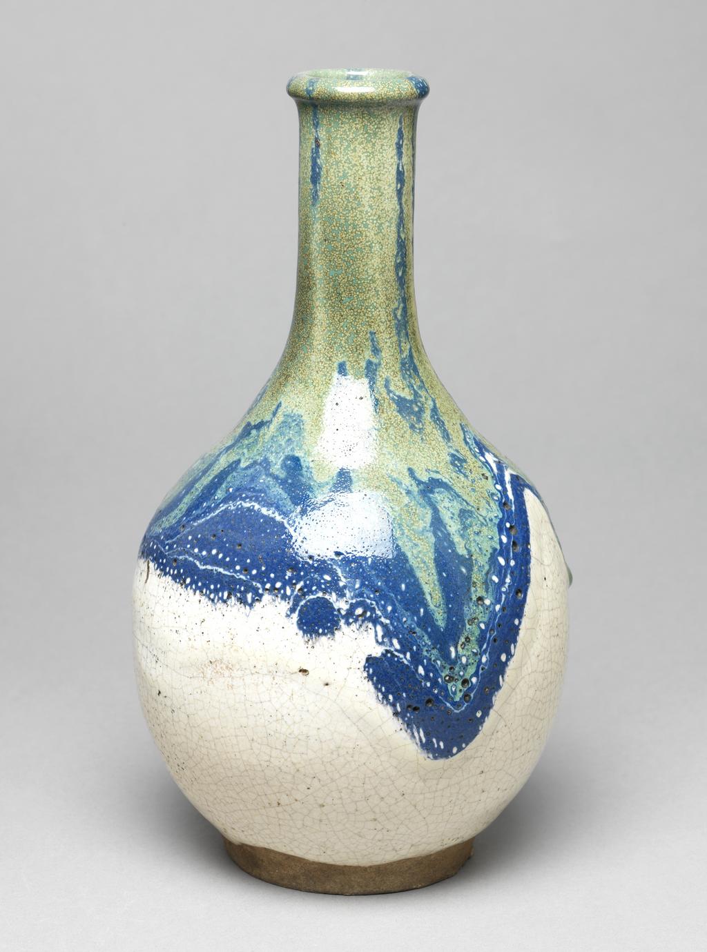 An image of Japanese pottery. Sake bottle. Unknown pottery, perhaps, Japan, Narita. Sake bottle of globular form with long neck. Buff body, thrown and turned. Cream glaze, the neck and shoulders covered with pours in blue and green. Heavy pitting visible. Stoneware, glazed, height 25.30 cm, diameter, rim, 4.30 cm, diameter, bottle, 14.10 cm, diameter, base, 8.20 cm, circa 1875-circa 1925. Meiji Period (1868-1912).