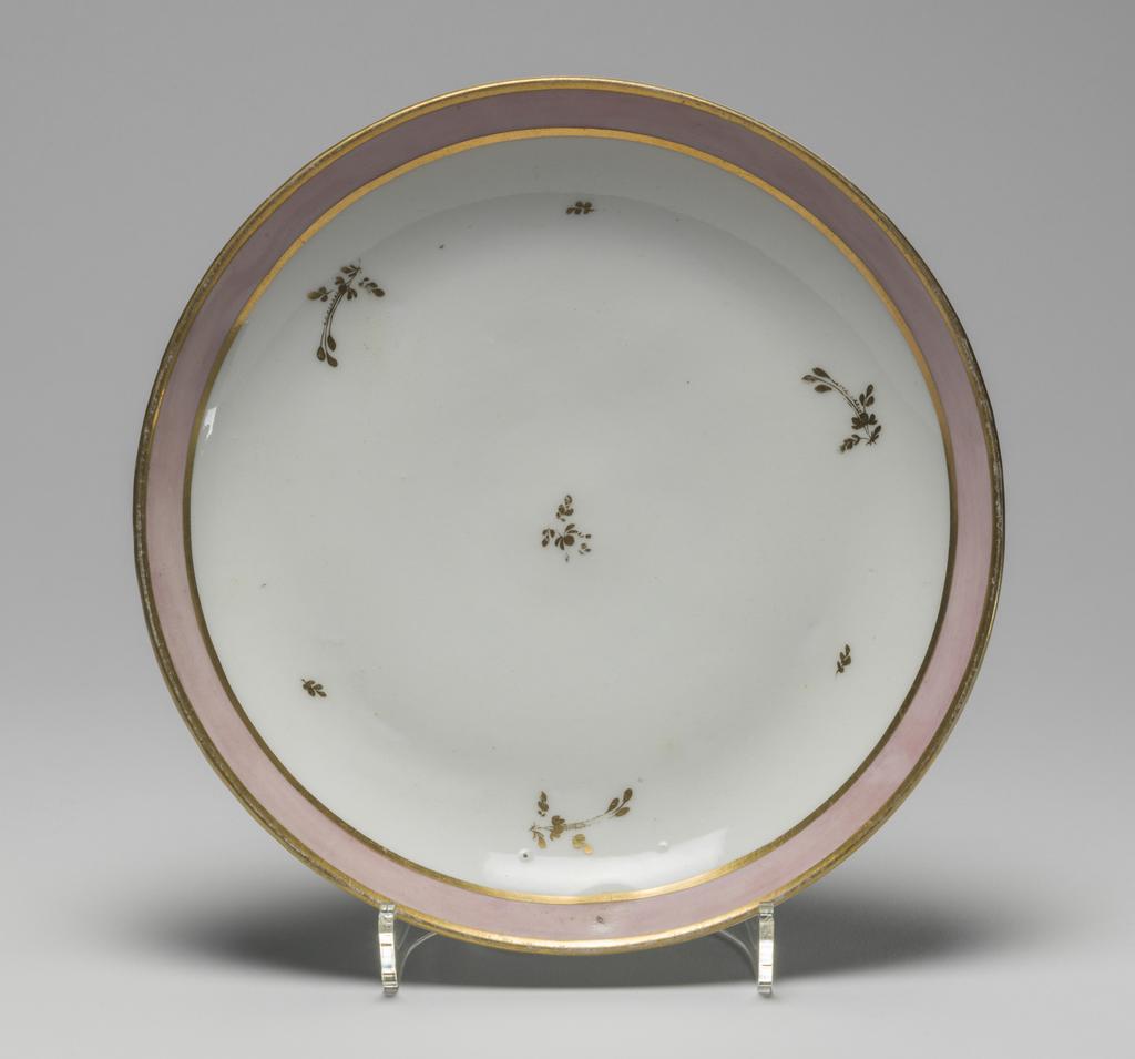 An image of Plate. New Hall Porcelain Factory, Staffordshire. Hybrid hard-paste porcelain plate, from a teaset. Decorated overglaze with a wide band of pink enamel between narrow gold bands and with scattered floral sprigs in gold. Pattern no. 223. Height 3.2 cm, diameter 23.8 cm, 1785. 
See C.11A-L-1988: A service comprising a teapot and cover of 'silver' shape, a milk jug, sugar basin and cover, a slop basin, two plates of different sizes, two tea bowls, two coffee cups and two saucers.