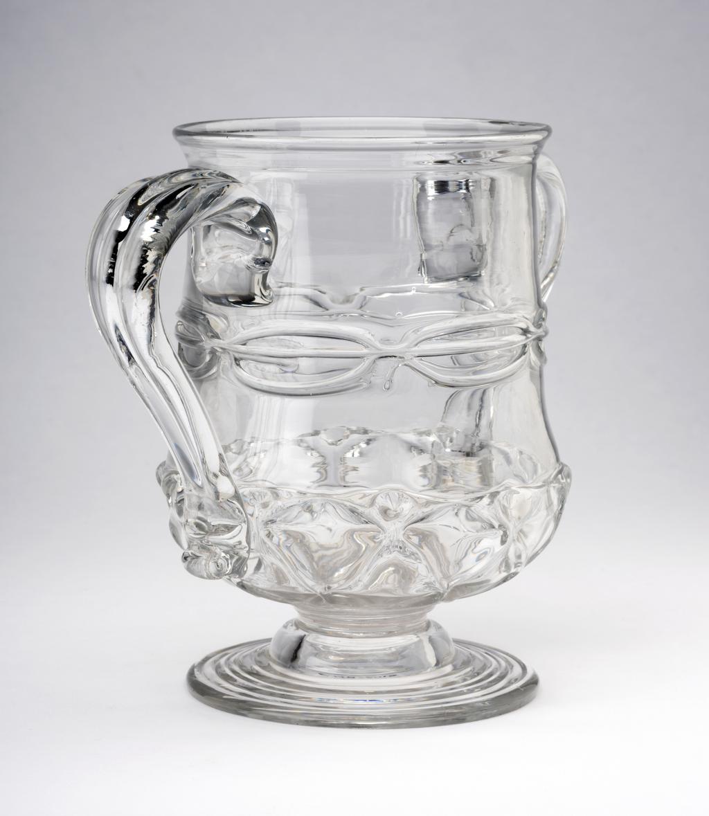 An image of Two-handled cup. Unidentified English glasshouse. The cup stands on a circular foot with a rough pontil mark underneath. The body is thistle-shaped with two applied loop handles.  The foot has indented rings. The lower part of the body is moulded with ribs, pincered into a repeating diamond pattern (nipt diamond-waies). The waist has three horizontally trailed threads pincered twice on each side and once under each handle to form a chain. The handles have a vertical ridge and a pincered kick at the bottom. Colourless lead-glass blown, pattern-moulded, pincered, and trailed. height, whole, 14.8 cm, width, whole, 20 cm, 1690-1710. Baroque. Sir Ivor and Lady Batchelor Bequest through The Art Fund.