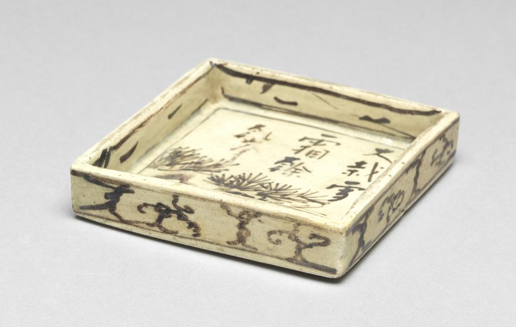 An image of Japanese pottery. Small plate for food. Kenzan, pottery studio, Japan, Kyoto. A square plate, small and shallow. Underglaze brushwork of pine in black, together with inscriptions in Chinese characters. Cloud decorations around the outside. Maker's mark and inscriptions in Chinese; on plate; brushed; five characters ( a short poem) describing the winter pine tree painted by KENZAN; the inscription is a five characters poem in Chinese describing the winter pine tree, it is painted by KENZAN; five characters read that the snow and frost still remaining on the big pine tree painted by KENZAN. Stoneware, hand-built, brush painting in black pigment, height 2.00 cm, width of the square, whole, 9.50 cm, larger, circa 1700-circa 1799. Edo Period (1615-1868). Production Note: this piece belongs to the three-piece set (C.183A, B & C-1934).