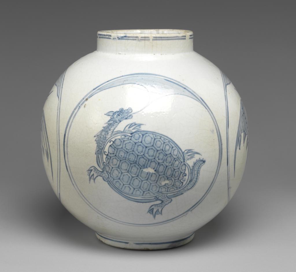An image of Large jar with tortoise and crane designs. Unknown pottery, Korea, Kwangju, Punwon-ri kilns. The body of this jar is almost globular and the neck straight; the foot is wider than the neck, giving the jar a stable appearance. In four roundels around the sides, divine tortoises and cranes are arranged in alternation, with a cloud or auspicious vapour issuing from the mouth of each tortoise, and with lots of free space around the designs. The glaze is of milky-white colour and crackled, the body is thick and heavy. On the base is an unexplained straight incised line and traces of sandy supports adhere to the footring. Porcelain, thrown, painted in cobalt-blue, and glazed, height, whole, 31.0 cm, diameter, rim, 14.0 cm, diameter, foot, 15.0 cm, circa 1750-1800. Choson Dynasty (1392-1910). Notes: Such jars (hangari) were used as wine vessels.