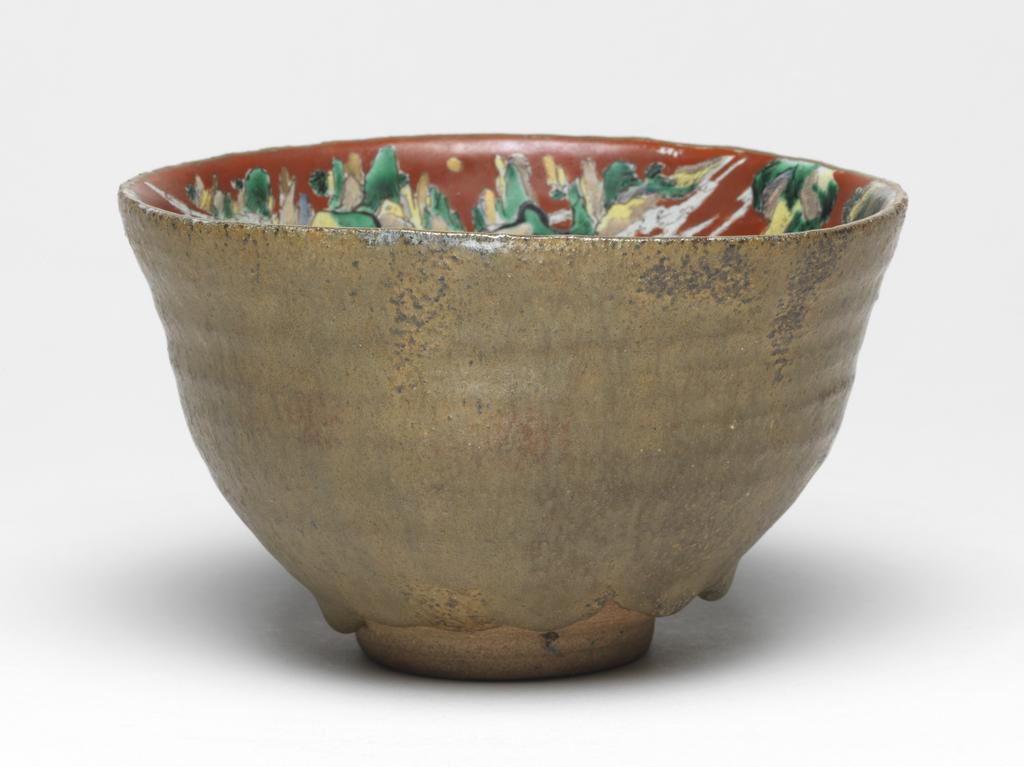 An image of Japanese pottery. Bowl. Aoki, Mokubei (Japanese, 1767-1833). Footed rough stoneware bowl, thrown and turned, with everted rim. The outside is plain with matt glaze of brown/yellow colour. The inside is highly decorated in enamels on a red background, with heavenly mountainous landscape, in which are many scholars, a bridge, dragon, pavilion, etc. Stoneware, thrown and turned, exterior with matt glaze of brown/yellow, interior brush painted green, yellow, brown and white, height, whole, 9.90 cm, diameter, rim, 16.00 cm, largest, diameter, foot, 6.20 cm, circa 1775 to circa 1825. Edo Period (1615-1868). Production Place: Japan, Kyoto.