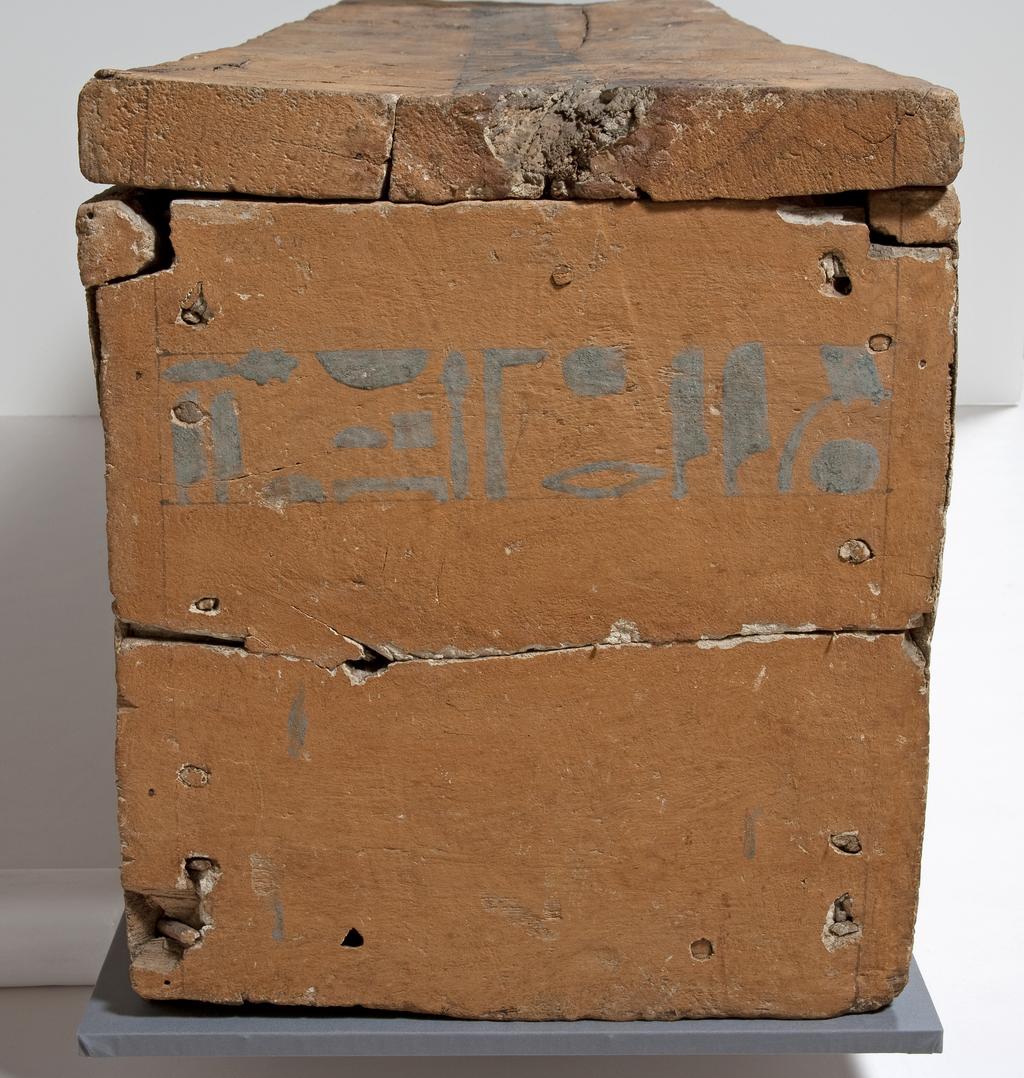 An image of Funerary Equipment. Coffin of Khety made of sycamore fig; part of one side is missing and original 'feet' lost; one line of painted text on lid and side; plastered wood painted with earth pigment. Black drafting lines still visible. Text sketched in back and coloured with Egyptian blue. An eye panel is painted on one side. Production Place: Egypt. Find Spot: Beni Hasan; 366. Wood, painted, height, 50, cm, length, 186, cm, width, 44.4, cm, ca 1990-1950 BC. Twelfth Dynasty; Middle Kingdom.