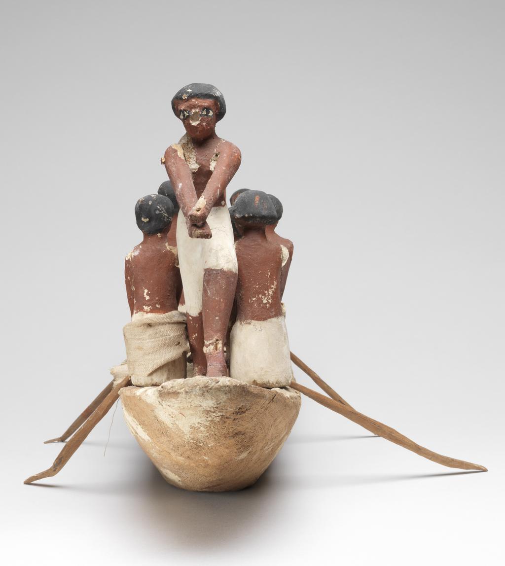 An image of Model Boat. Wooden model of a rowing boat with seven oarsmen (one missing at the front); a look-out on the prow; and a stroke caller (cox) in the bow. He sits beside a rudder-oar. The figures have white painted kilts and red-brown flesh. Some figures have real linen loin cloths. Production Place: Egypt. Find Spot: Tomb of Khety, tomb 366 (Beni Hasan), Egypt. Painted wood, linen, height, 25 cm, length 59 cm, width 12 cm, circa 2010-circa 1950 B.C. 12th Dynasty, Middle Kingdom.