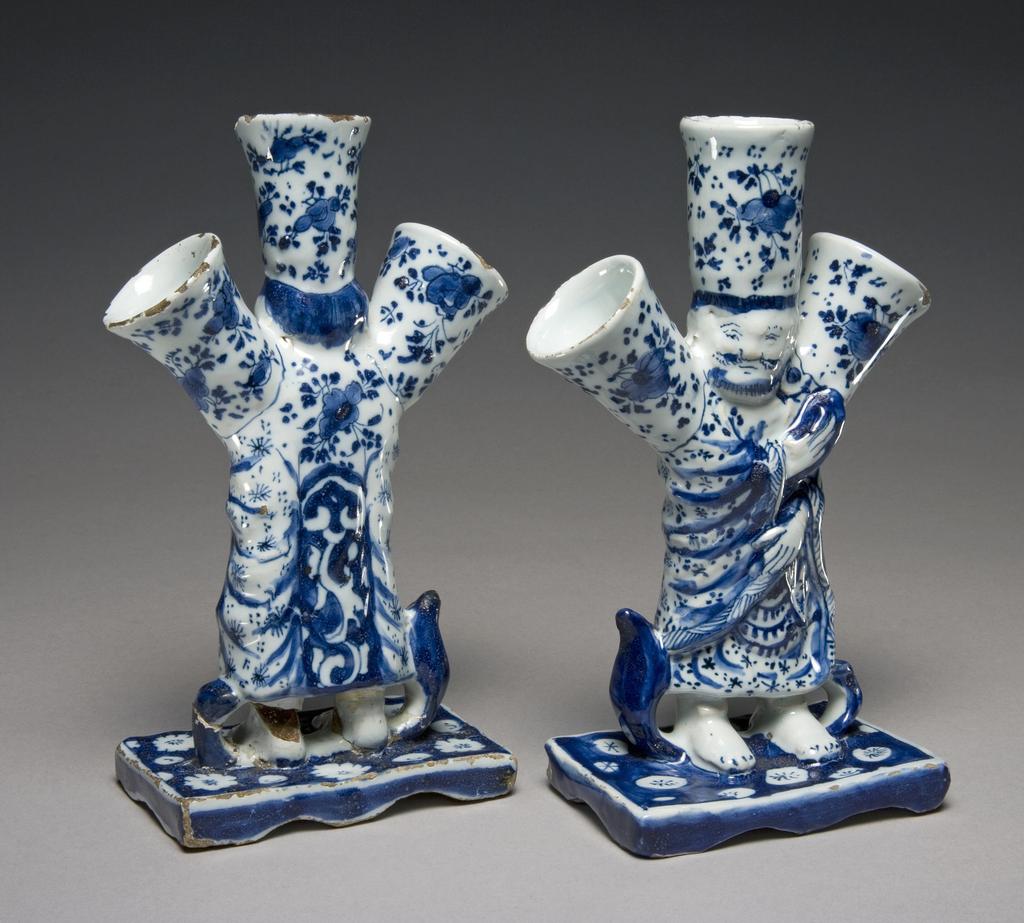 An image of Description: 2 Flower vases in the form of a Chinese sage or deity with three spouts for flowers on his head and shoulders, of tin-glazed earthenware painted in blueProduction Place: Delft (factory), United Provinces of the Netherlands (country) Dimensions:  height (Both): (whole): 18 cmDate: circa 1700 to 1725     
