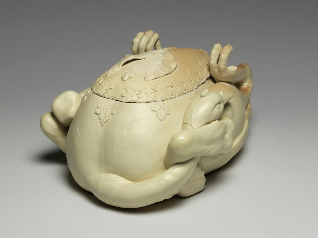 An image of Tureen and cover. ‘Pastry turkey’ tureen. John and William Turner, pottery, Staffordshire, Longton, Lane End. Moulded in the shape of a trussed and roasted fowl or game bird, breast upwards, with upturned feet and head tucked under one wing and egg-shaped cover fitting into breast. There is a relief moulded parsley garnish around the junction of the cover and body, and three moulded bay leaves which form a handle for the cover. Faint reddish-brown staining suggests roasting on parts of the upper surface. The interior is glazed. The underside is very slightly concave, with a narrow foot-rim. Cream stoneware, moulded, modelled and decorated with applied reliefs, height, whole, 15.5 cm, approx, length, whole, 33.6 cm, width, whole, 20.0 cm, approx, circa 1800. Production Note: Not dated, but social circumstances at this time indicate c.1800 the most likely date. Other examples dated c.1780-c.1820.