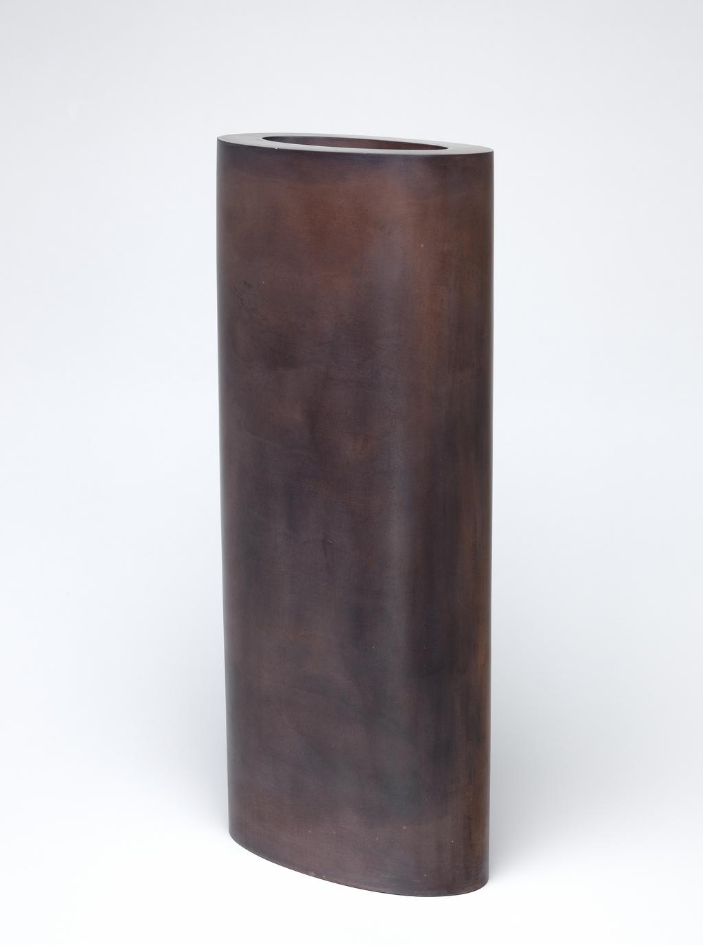 An image of Tall Ellipse in Deep Reds. Rena, Nicholas (British, b. 1963). Tall elliptical vessel with straight sides and thick walls. The upper rim is perfectly flat. The outside and much of the inside is burnished to an exceptionally smooth finish and stained red-brown; the stain is applied unevenly, giving an organic appearance. The underside is flat, burnished and stained. Earthenware, press moulded, sanded and burnished, stained, heigth 43 cm, width 19.4 cm, depth 10 cm, c. 2000. Acquisition Credit: Given by Nicholas and Judith Goodison through The Art Fund.