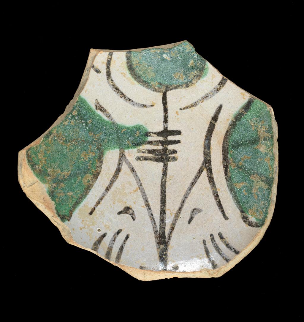 An image of Tin-glazed Earthenware / Fragment. Unknown. Buff earthenware, the reverse lead-glazed yellowish-brown except for the base, the front tin-glazed greyish-white; painted in black and green. Height (whole) 2.9 cm, width (whole) 9.4 cm, circa 1250-1400. Umbria, Orvieto, Italy.
