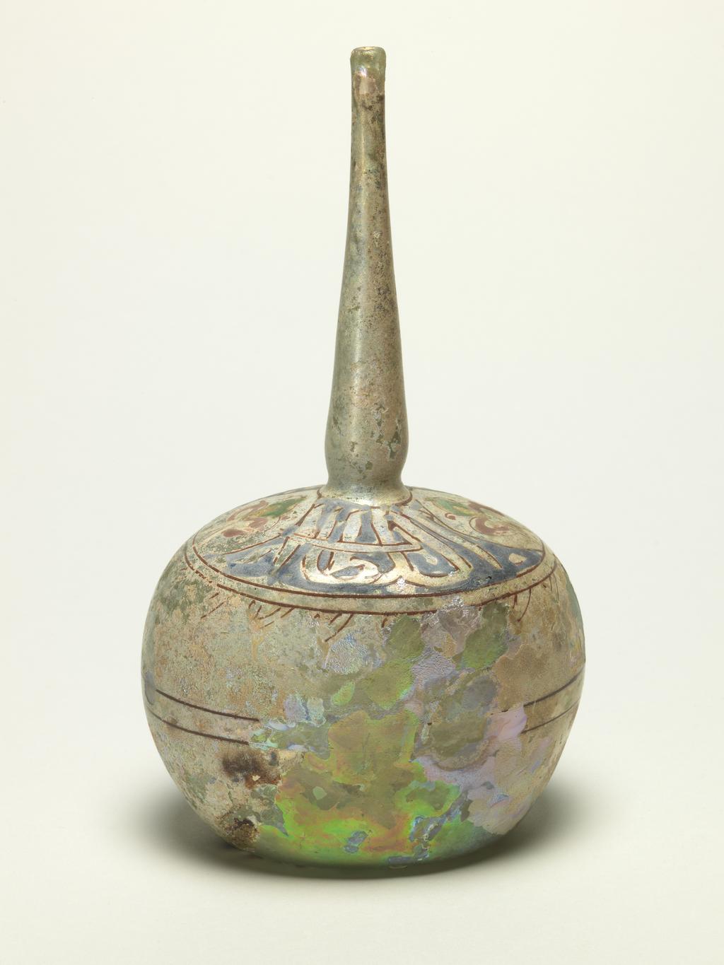 An image of Sprinkler Bottle. Unknown production, Syrian or Egyptian. Enamelled on the shoulder in blue, green, yellow and red with lotus flowers and the inscription 'Glory to our Lord, the Sultan'; traces of two bands of red enamel around the body. Clear blown glass with green tinge, enamelled, height, whole, 28.0 cm, diameter, whole, 11.5 cm, circa 1300-1400.