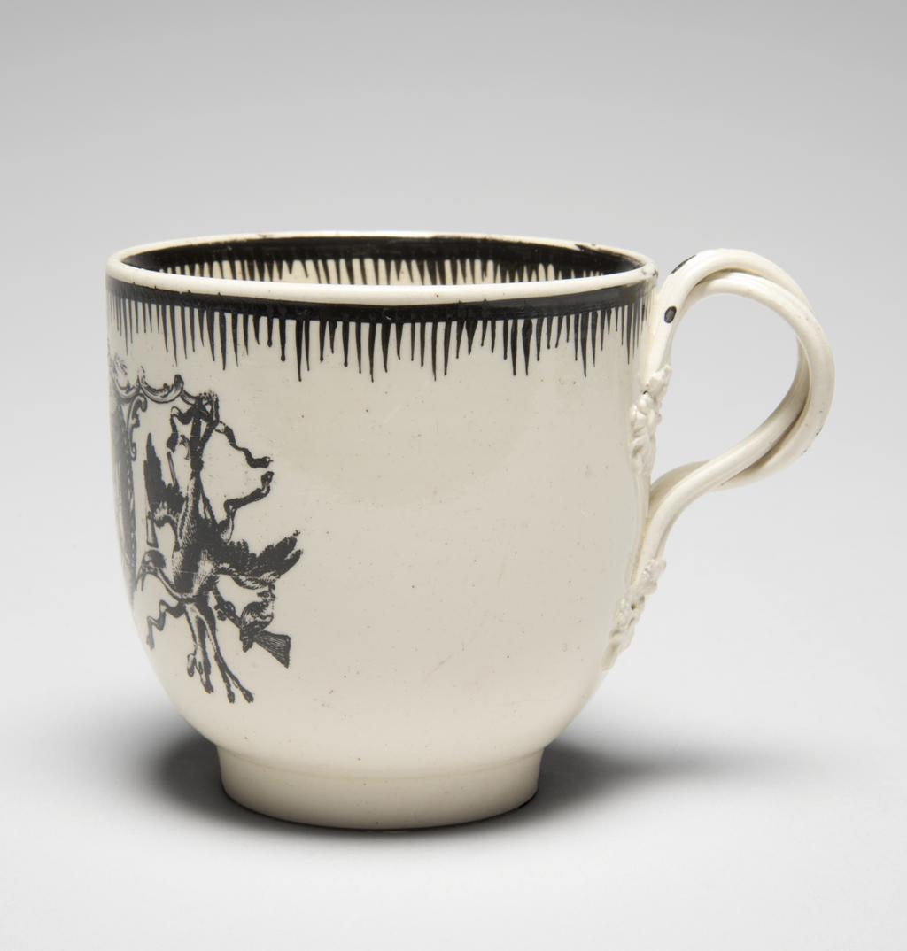 An image of Creamware chocolate cup and saucer, with Minerva and emblems of Wisdom and Industry. Neale & Co., factory, perhaps, Staffordshire. Leeds Pottery, factory, perhaps, Yorkshire. The cup stands on a low footring from which its sides curve outwards and then almost vertically upwards to the rim; reeded double intertwined loop handle with flower and leaf terminals. The saucer has a low footring and deep, concave curving sides. The front of the cup and the centre of the saucer are transfer-printed with a medallion with a medallion enclosing a figure of Minerva, various emblems of Wisdom and Industry and the motto 'LET WISDOM UNITE US', flanked by trophies of game. The interior of the cup is painted with an eight-petalled, stylised flower. Borders on both cup and saucer are composed of a horizontal band from which run close, vertical lines of varying lengths so as to form a rough zig-zag below the band. Cream-coloured earthenware, transfer-printed overglaze and painted in jet black. Pale yellow lead-glaze, inclining towards green where it lies thickly within the footrings. The base and exterior of the cup are lightly crazed with a fine mesh. Height, cup, 6.8 cm, diameter, saucer, 12.6 cm, circa 1780. Rococo.