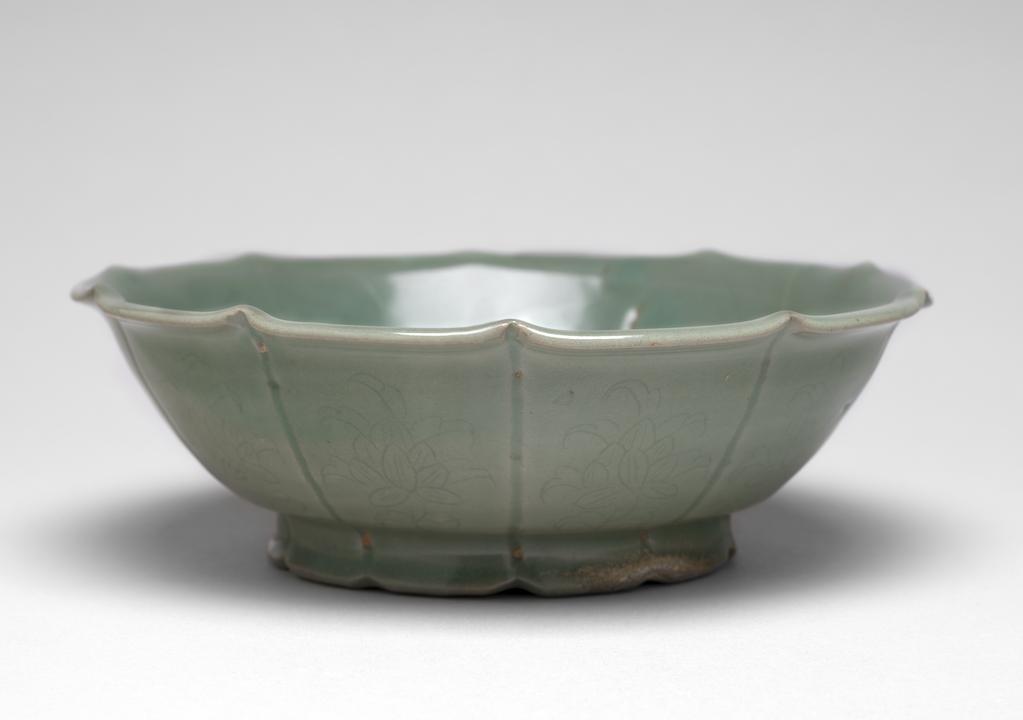 An image of Basin. Unknown pottery, Korea, North Cholla province. Puan-gun, Yuch'on-ri kilns or Kangjin-gun, Sadang-ri kilns. The ten-lobed flower-shaped basin has a deeply lobed, flared rim, and a flared foot carved in ten petal-shaped divisions; on the outside the lobes are defined by carved lines and incised with lotus sprays, while the inside is incised with a large overall lotus leaf. The basin has three neat quartzite spur-marks on the base. Stoneware, thrown, indented, incised and celadon-glazed. Height, whole, 6.5 cm, diameter, mouth, 18.4 cm, diameter, foot, 10.0 cm, circa 1150-1200.  Koryo Dynasty. Production Note: This is a rare example of a ewer accompanied by a basin. It is most likely to date from the mature period of Koryo celadon in the second half of the twelfth century, and to have been made either at Sadang-ri, Kangjin, or at Yuch'on-ri, Puan. See ewer and cover C.52 & A-1984.