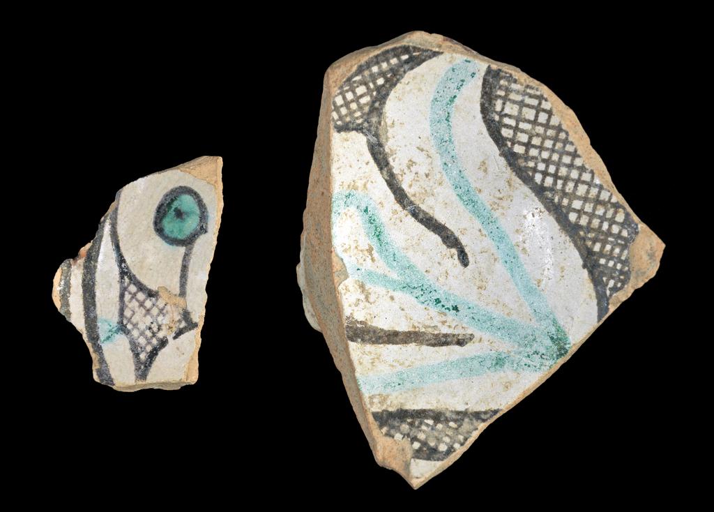 An image of Fragments of a maiolica bowl. Unknown (pottery). Pinkish-buff earthenware, tin-glazed white overall except for the base, painted in dark manganese-brown and pale green, height 2.5cm, length 8.8cm, width 7.0cm, circa 1250-1400. Umbria, Italy.