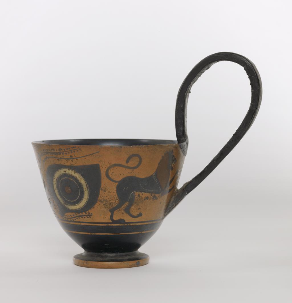 An image of Vessel. Kyathos, Dionysos and lions. Production Place: Athens, Attica, Greece. Clay, black-figured, height 0.076 m, diameter, rim, 0.099 m, diameter, base, 0.049 m, height 0.131 m, 500 B.C. Archaic Period.