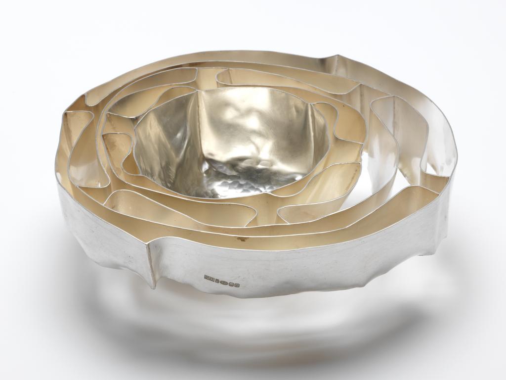 An image of Contemporary Craft. Cherry Bowl. Dorph-Jensen, Sidsel, silversmith (b. Nyborg, Denmark, 1973). The central bowl raised, the surrounding areas formed by manipulated ribbons of silver, The almost round bowl has hammer marks around the centre. It is surrounded by five ribbons of graduated height wavying and looping back on each other, and extending outwards further on one side of the bowl than the other. There is a cusp on opposing sides of the outer, narrowest ribbon. Silver, raised, manipulated and soldered, height, overall, 5.7 cm, width, overall, 17.6 cm, weight, whole, 585 g, 2006. Gift of Nicholas and Judith Goodison through The Art Fund.