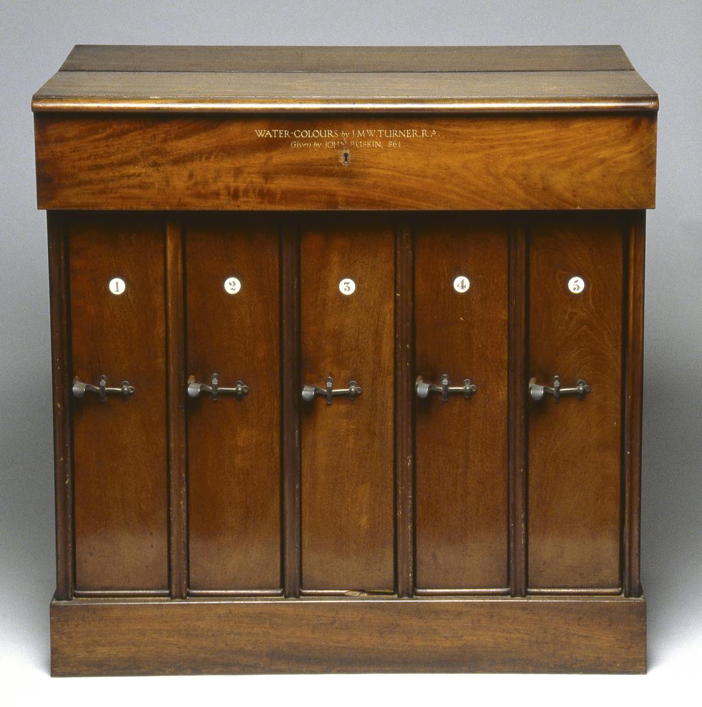 An image of Furniture / Drawing Cabinet. Snell, William and Edward. Mahogany cabinet with brass mounts and ivory plaques, with five removable vertical cases, each case containing five removable glazed oak frames for drawings. The top has a flange at the front inscribed in gold lettering 'WATER-COLOURS by J.M.W.TURNER, R.A./Given by JOHN RUSKIN, 1861.' Height (overall) 76.5 cm, height (plinth) 10 cm, width 78.2 cm, depth 52.7 cm, height (frames) 51.2 cm, width (frames) 43 cm.