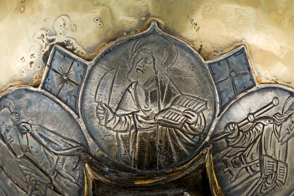 An image of Silver/Church Plate. Chalice. Petruccio Campagnini, Andrea, probably (active Tuscany, Siena, Italy). Set with six silver medallions of Christ, St Peter, St. Paul, St. John, St. Bartholomew and possibly St. Barnabus. Above the knop the stem is engraved with six male busts without nimbi; below the knop the stem is engraved with six birds. At the base of the stem are moulded borders containing a plain band engraved and enamelled with the inscription 'ANDREA * PETRUCI * DE * SENIS * ME *FECI(T). The low copper-gilt trumpet-shaped foot has a shaped circular spreading base with rim of twelve alternating semicicular and pointed lobes. It is set with six applied silver plaques with translucent enamels on sunk relief, representing the Crucifixion with Instruments of the Passion, on either side of which are the Virgin and St. John; on the opposite side are a bishop with mitre and crozier between a male and female saint. Above are smaller shaped triangular plaques enamelled with the heads of angels; and below are lozenge shaped plaques enamelled with a stylised leaf. The base stands on a foot ring decorated with moulded, beaded and dentil borders. Bowl silver-gilt with silver calyx, foot and stem of copper-gilt, decorated with embossing and chasing, and set with silver plaques with basse taille enamelling, height, overall, 19 cm, diameter, base, 12.8 cm, maximum, diameter, rim, 9.9 cm, circa 1370. Late Medieval. Gothic.