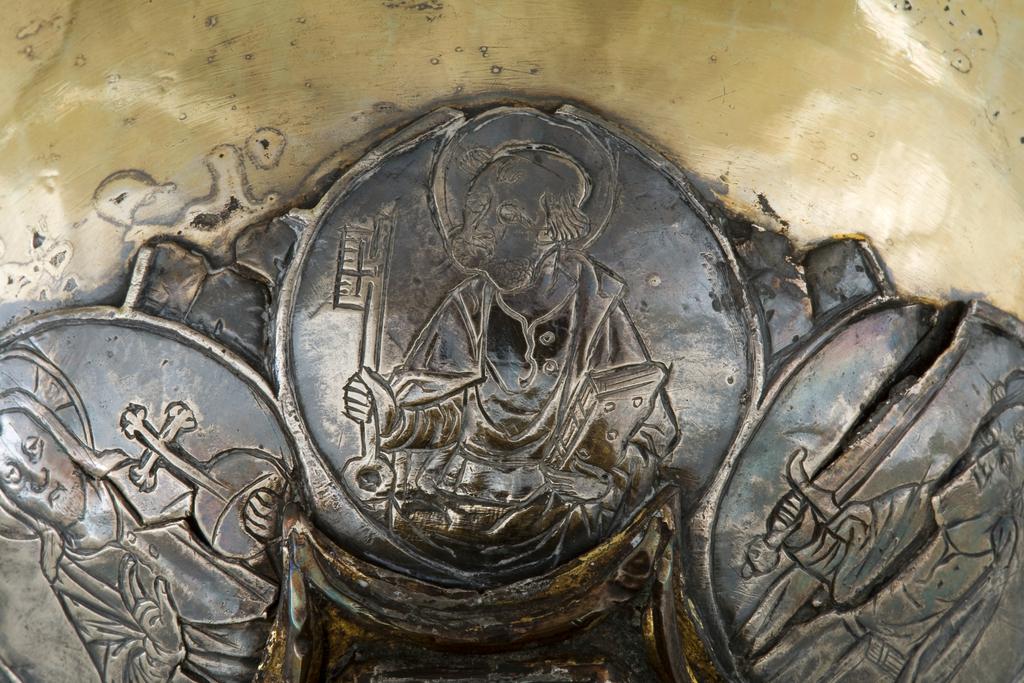 An image of Silver/Church Plate. Chalice. Petruccio Campagnini, Andrea, probably (active Tuscany, Siena, Italy). Set with six silver medallions of Christ, St Peter, St. Paul, St. John, St. Bartholomew and possibly St. Barnabus. Above the knop the stem is engraved with six male busts without nimbi; below the knop the stem is engraved with six birds. At the base of the stem are moulded borders containing a plain band engraved and enamelled with the inscription 'ANDREA * PETRUCI * DE * SENIS * ME *FECI(T). The low copper-gilt trumpet-shaped foot has a shaped circular spreading base with rim of twelve alternating semicicular and pointed lobes. It is set with six applied silver plaques with translucent enamels on sunk relief, representing the Crucifixion with Instruments of the Passion, on either side of which are the Virgin and St. John; on the opposite side are a bishop with mitre and crozier between a male and female saint. Above are smaller shaped triangular plaques enamelled with the heads of angels; and below are lozenge shaped plaques enamelled with a stylised leaf. The base stands on a foot ring decorated with moulded, beaded and dentil borders. Bowl silver-gilt with silver calyx, foot and stem of copper-gilt, decorated with embossing and chasing, and set with silver plaques with basse taille enamelling, height, overall, 19 cm, diameter, base, 12.8 cm, maximum, diameter, rim, 9.9 cm, circa 1370. Late Medieval. Gothic.