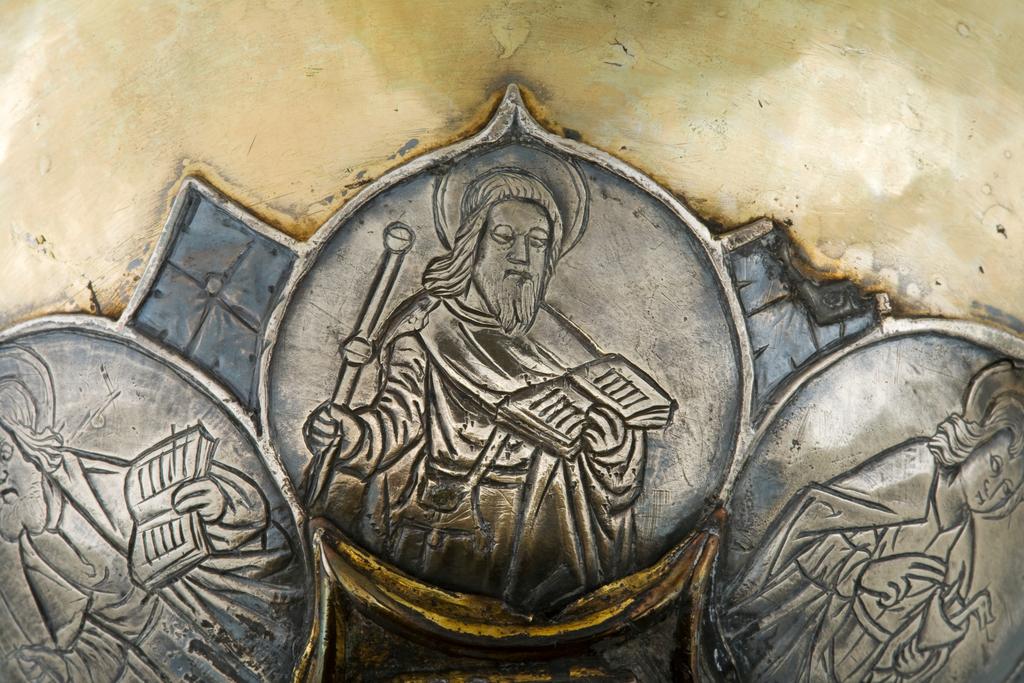 An image of Silver/Church Plate. Chalice. Petruccio Campagnini, Andrea, probably (active Tuscany, Siena, Italy). Set with six silver medallions of Christ, St Peter, St. Paul, St. John, St. Bartholomew and possibly St. Barnabus. Above the knop the stem is engraved with six male busts without nimbi; below the knop the stem is engraved with six birds. At the base of the stem are moulded borders containing a plain band engraved and enamelled with the inscription 'ANDREA * PETRUCI * DE * SENIS * ME *FECI(T). The low copper-gilt trumpet-shaped foot has a shaped circular spreading base with rim of twelve alternating semicicular and pointed lobes. It is set with six applied silver plaques with translucent enamels on sunk relief, representing the Crucifixion with Instruments of the Passion, on either side of which are the Virgin and St. John; on the opposite side are a bishop with mitre and crozier between a male and female saint. Above are smaller shaped triangular plaques enamelled with the heads of angels; and below are lozenge shaped plaques enamelled with a stylised leaf. The base stands on a foot ring decorated with moulded, beaded and dentil borders. Bowl silver-gilt with silver calyx, foot and stem of copper-gilt, decorated with embossing and chasing, and set with silver plaques with basse taille enamelling, height, overall, 19 cm, diameter, base, 12.8 cm, maximum, diameter, rim, 9.9 cm, circa 1370. Late Medieval. Gothic.