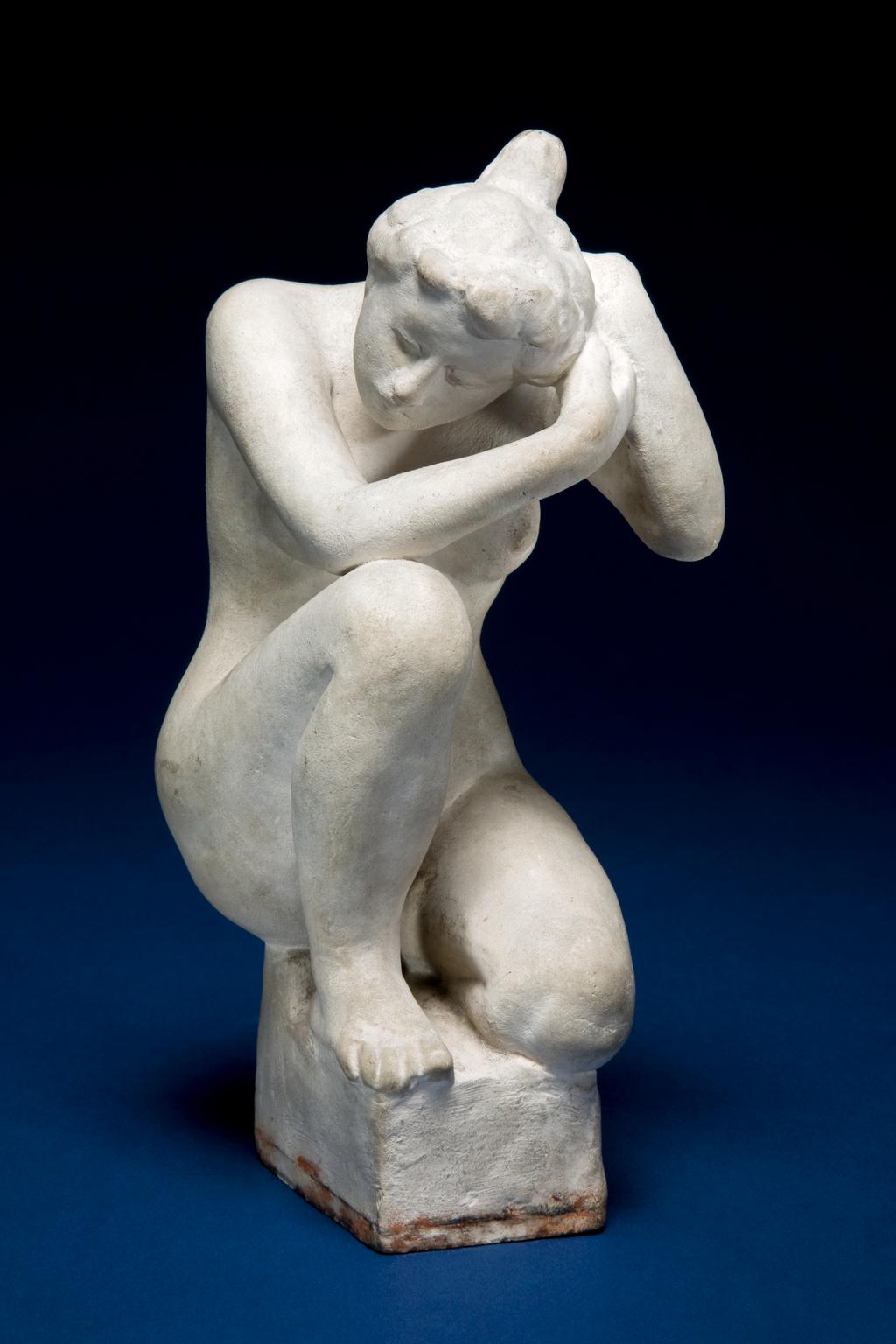 An image of MAILLOL, Aristide'Petite Baigneuse Accroupie'Little Bather  SquattingOff-white terracotta figure of a nude woman with her hair swept up into a bun on the top of the back of her head. She sits on a rectangular pedestal with her left leg bent under her and her right knee bent and raised. Her head is tilted downwards, and she touches its left side with both hands, as if adjusting her hairFranceC.1900