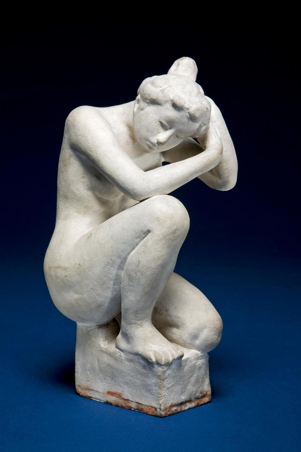 An image of MAILLOL, Aristide'Petite Baigneuse Accroupie'Little Bather  SquattingOff-white terracotta figure of a nude woman with her hair swept up into a bun on the top of the back of her head. She sits on a rectangular pedestal with her left leg bent under her and her right knee bent and raised. Her head is tilted downwards, and she touches its left side with both hands, as if adjusting her hairFranceC.1900
