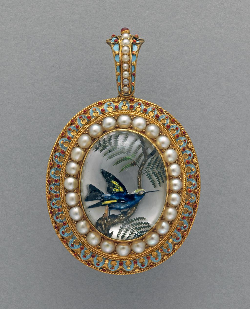 An image of Thomas, William James. Reverse crystal intaglio of a bird on a branch mounted in gold, enamelled in pale blue and red and set with pearls. Oval with a loop for suspension at the top, decorated en suite with the mount. Behind the intaglio there is a compartment for a phototgraph or hair. The back of the mount is engraved with the word 'Vienna' and the date '1873'.