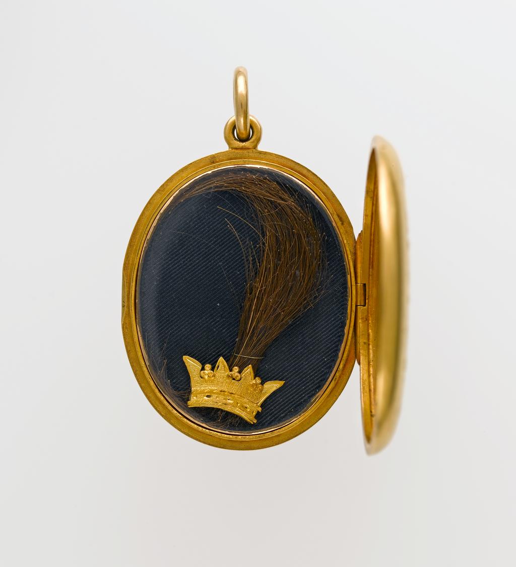 An image of Jewellery/Locket. Gold, hair (of Charles I), black silk. Oval locket with the script monogram CR, with crown above mounted in gold on the plain surface. Inside, on black silk and under flat glass, a lock of hair and a crown in gold. After 1813. English.