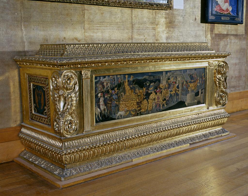 An image of Furniture. Cassone of carved, gessoed and gilt wood, with a painted panel of The Triumph of Scipio by Apollonio di Giovanni (1415-65), the sides with panels painted with coats of arms. Height (whole) 38¼ in, width 80 3/4 in, depth 29 in, circa 1801 to 1900. Production Place: Florence, Italy.