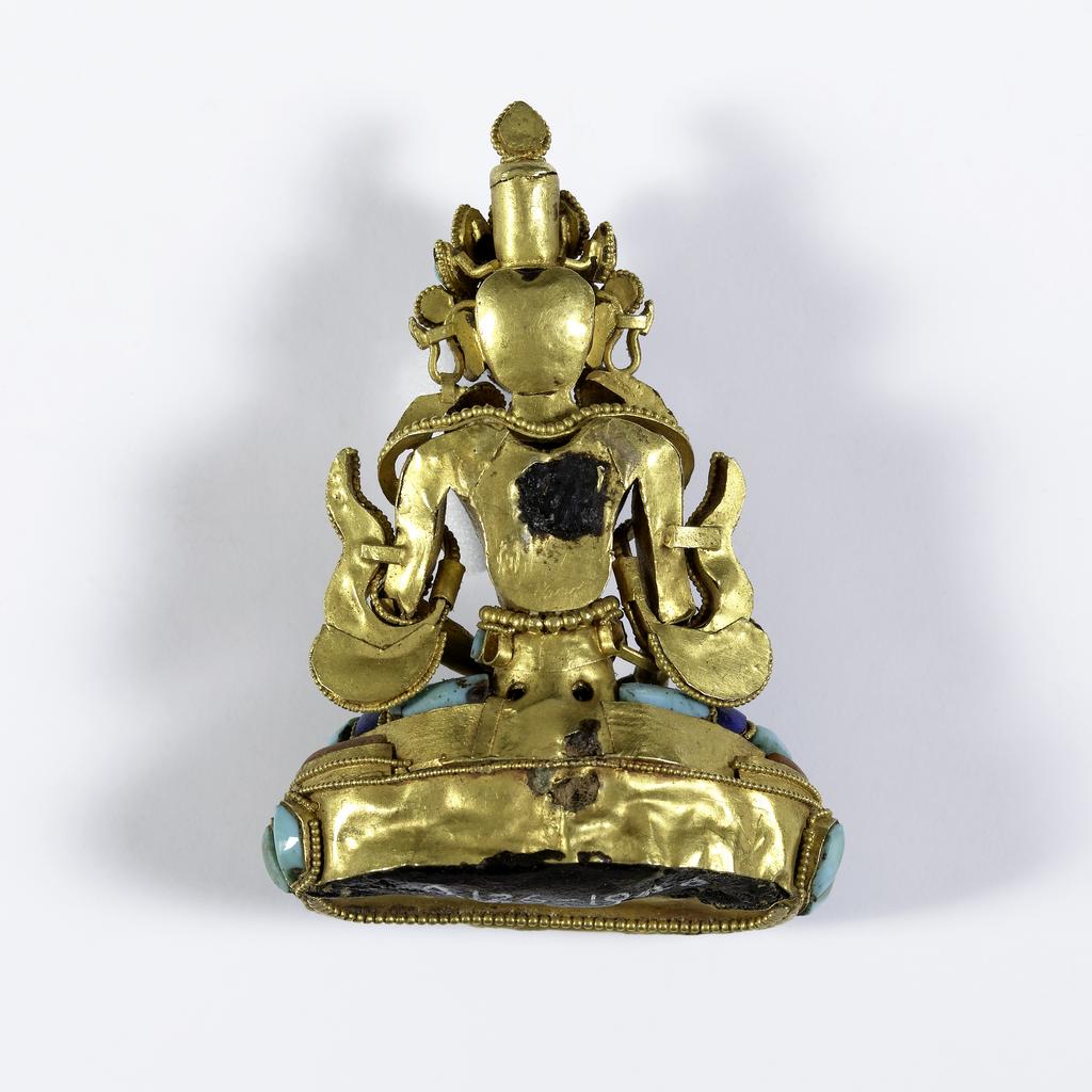 An image of Sculpture. Figure of the Buddha, made from carnelian, lapis lazuli and gold. He is seated on an open lotus flower. Carving, height 4.4 cm. Chinese.