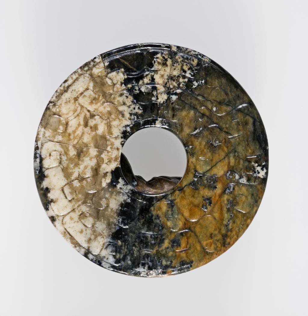 An image of Jade pendant. In archaistic style, decorated with a feline dragon in relief. Nephrite, diameter 5.9 cm, 1800-1900. Chinese.