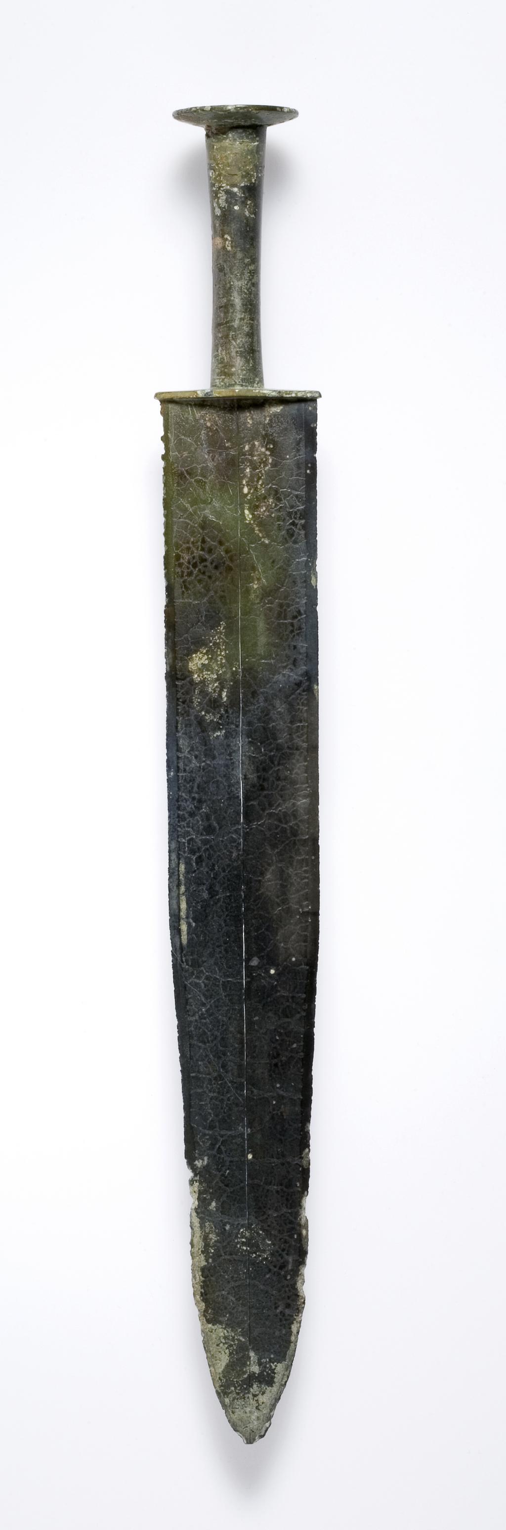 An image of Weapons/Sword. Bronze, handle terminated by a small jade pommel. Double edged, tapering blade, black and green. Bronze sword inlaid with jade pommel. Nephrite, diameter, 1.9 cm, 400-300 B.C. Chinese.