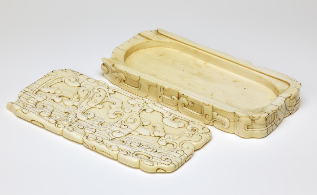 An image of Ink-stone case with sliding lid, ivory carved in low relief on the top and sides with archaistic motifs. Production Place: China. Ivory, carved. 19th century. Sir Victor Sassoon Chinese Ivories Trust.